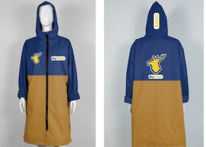 The image shows a changing robe by Dry Stag. It is a hooded robe with a two - tone design, featuring blue on the top and brown on the bottom. The robe has a front zipper, and the Dry Stag logo, which includes a stag head, is prominently displayed on the chest and back.