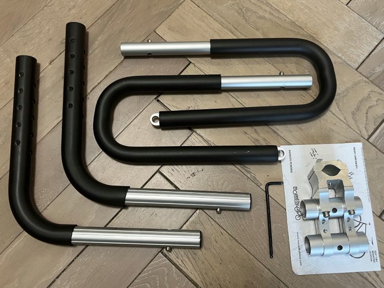 Disassembled surfboard bike rack with aluminum clamps, U-arms, and instruction manual