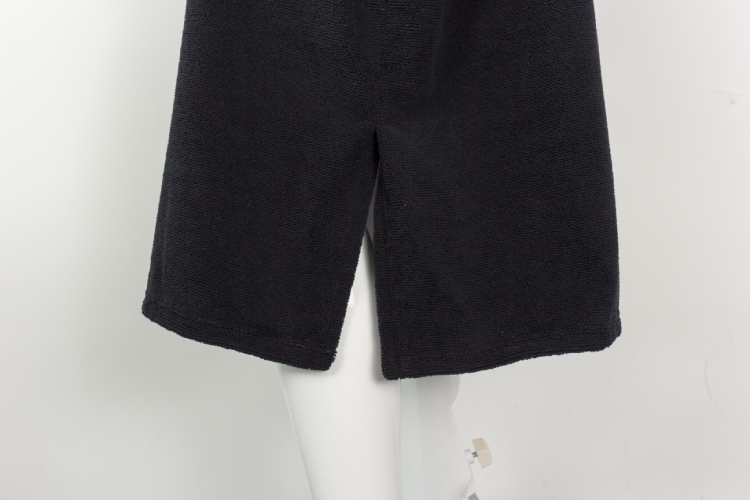 Bottom hem slit detail of black surf poncho.