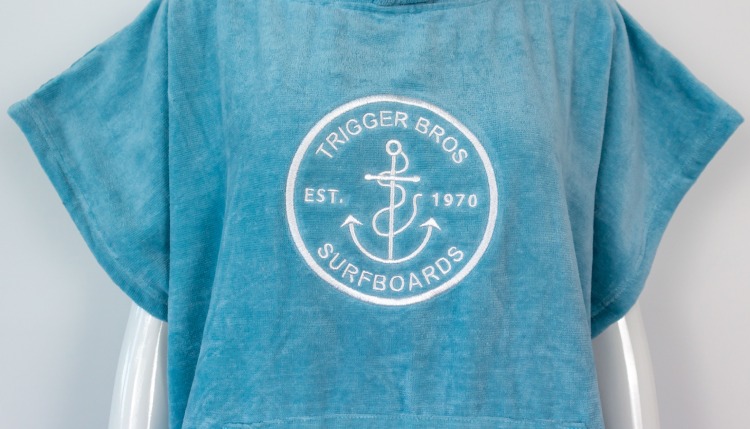 Blue cotton surf poncho with white Trigger Bros Surfboards embroidery on chest