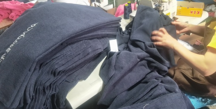 Bulk navy poncho production and embroidery in progress