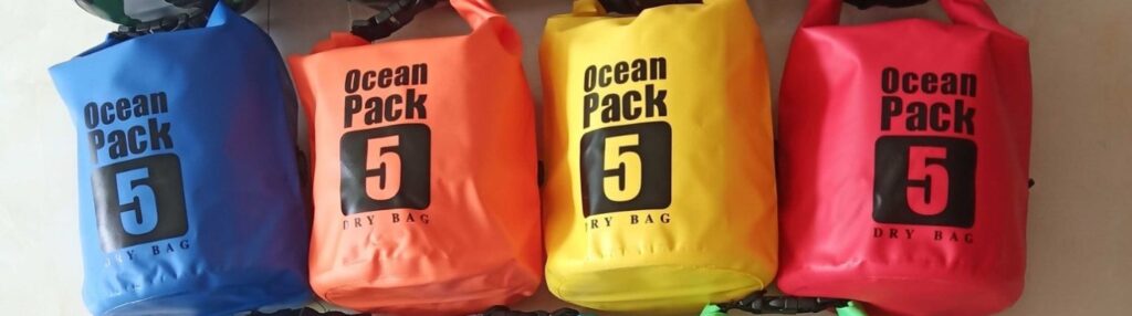 Assorted colorful 5L dry bags hung in a row, perfect for water sports and beach storage.