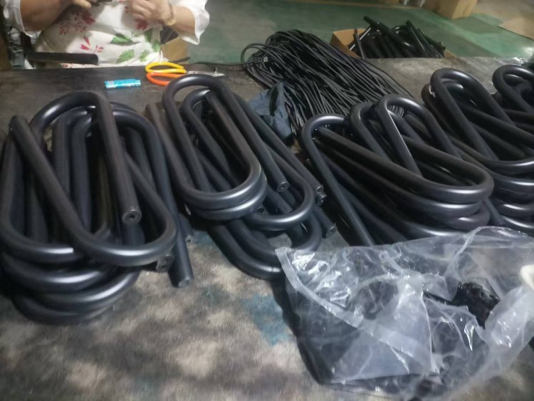 Surfboard rack U-shaped tubes wrapped with protective foam being assembled by worker in factory
