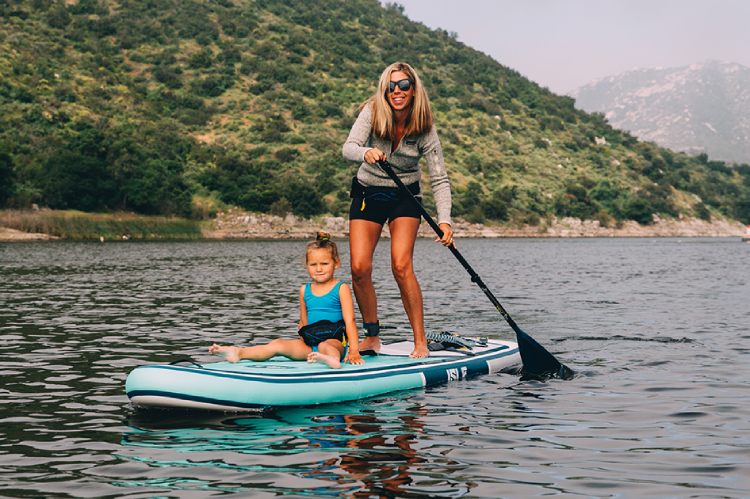 Mother and child paddling on an inflatable SUP board on a scenic lake