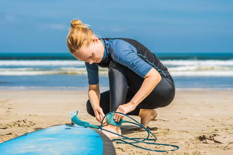 Surfer wearing an ankle surfboard leash on the beach