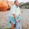 Surfer using two-tone hooded surf poncho for discreet beach changing after session