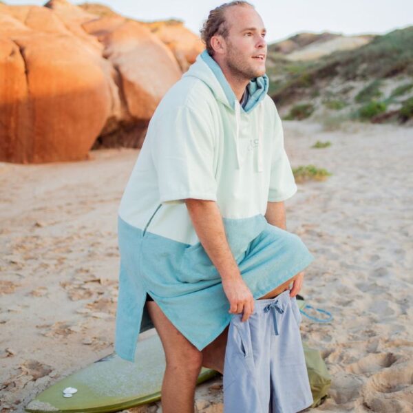 Surfer using two-tone hooded surf poncho for discreet beach changing after session