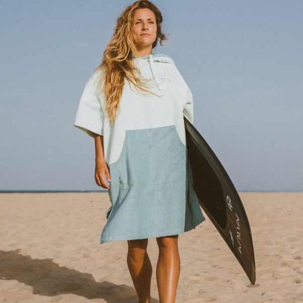 Confident surfer holding board in soft cotton two-tone surf poncho on beach