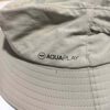 _cuva This image shows the brand label on the surf fishing hat. The label reads "AQUAPLAY" and is located on the side of the hat, which is light beige with a wide brim.